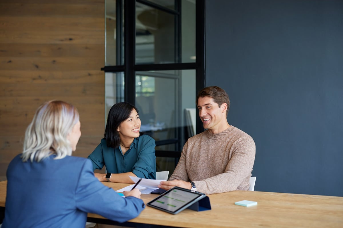 Smiling multiethnic couple receiving financial guidance from advisor with copy space