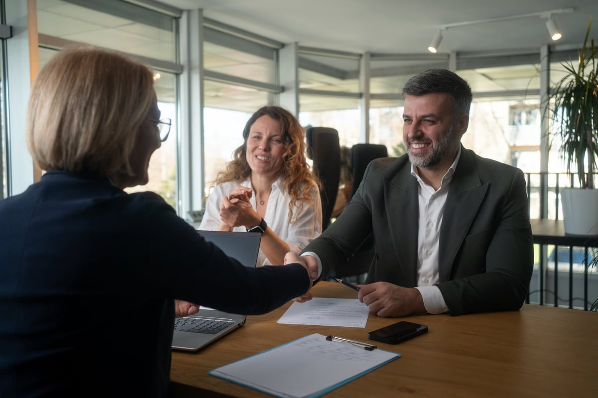 Young happy couple came to a successful agreement with their agent during a meeting in the office.